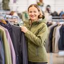 Swara Abliz toont wandelkleding naast een rek in de sportwinkel