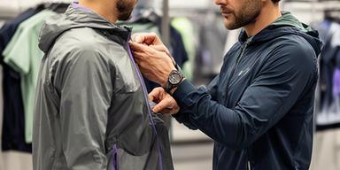 Sportadviseur Henck Landsmeer die een hardloper helpt met kleding