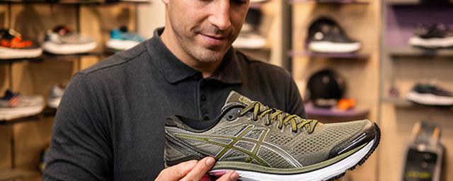 Sportadviseur die een hardloopschoen bekijkt in de winkel van Westervoort